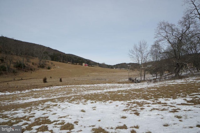 yard covered in snow featuring a rural view and a mountain view