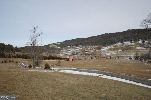 yard covered in snow with a rural view and a mountain view