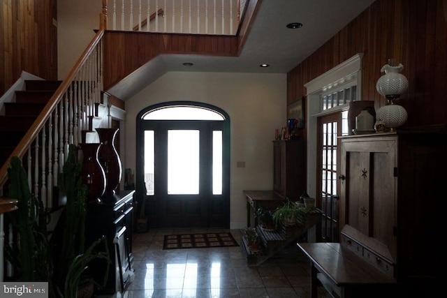 foyer featuring tile patterned floors, wooden walls, and stairs