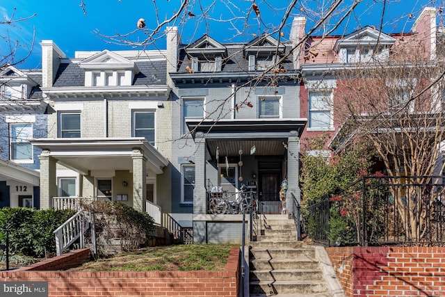 view of front of home featuring brick siding, a high end roof, mansard roof, and a porch