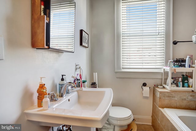 full bath with a relaxing tiled tub, a sink, and toilet