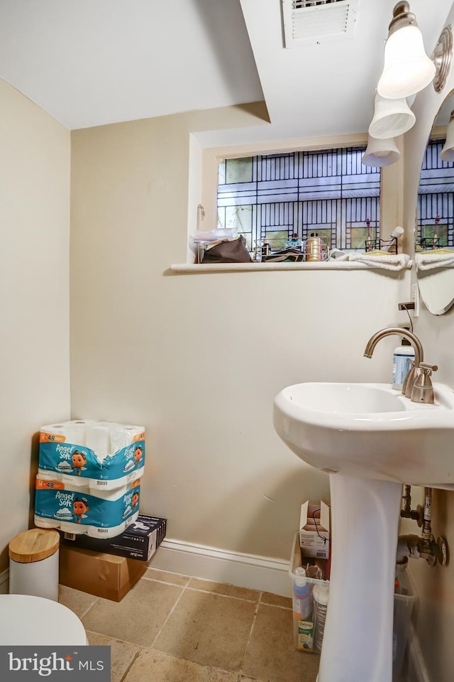 half bath with toilet, visible vents, and baseboards