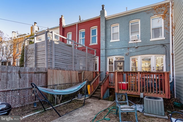 rear view of house with a deck, brick siding, cooling unit, and fence