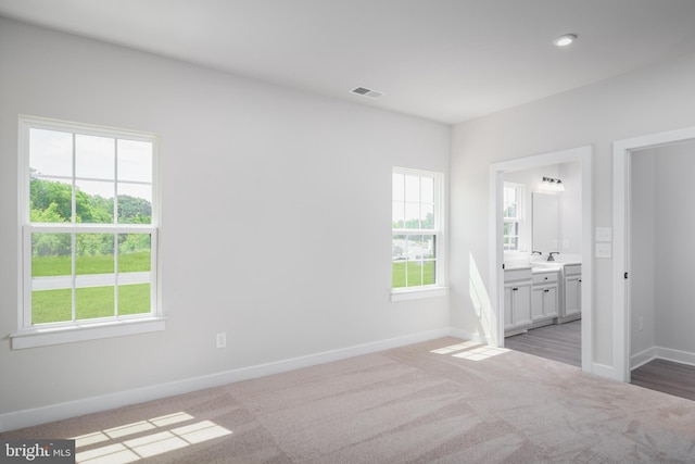 unfurnished bedroom with light carpet, ensuite bath, visible vents, and baseboards