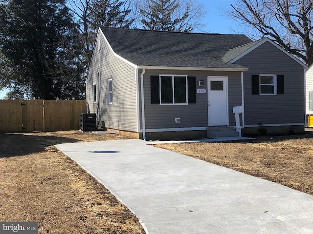 view of front of home with entry steps, a shingled roof, cooling unit, and fence