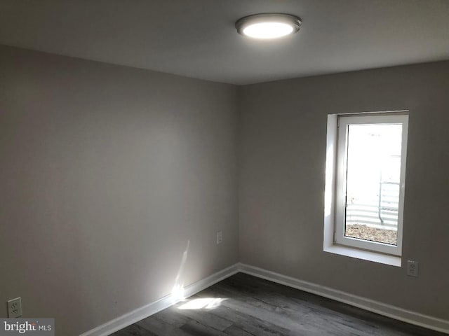 unfurnished room featuring dark wood-style flooring and baseboards