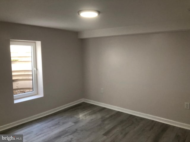 empty room with dark wood-style flooring and baseboards