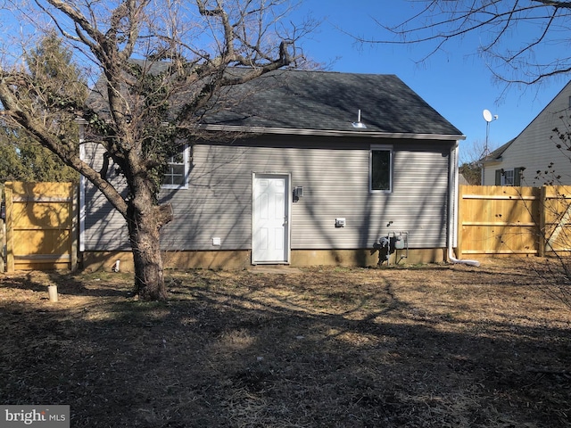 back of house with roof with shingles and fence