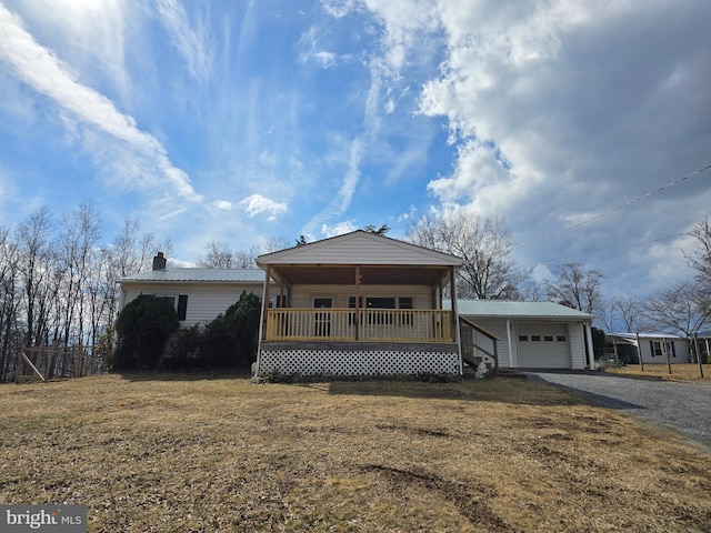 view of front of property with gravel driveway, covered porch, metal roof, and a front lawn