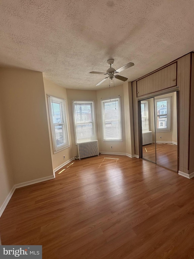 unfurnished bedroom with radiator, a textured ceiling, and wood finished floors
