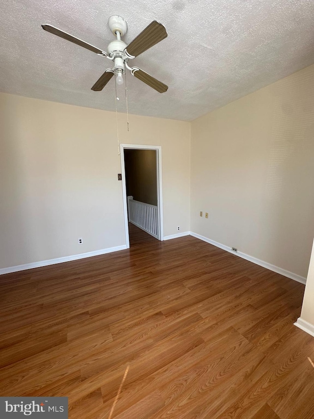 unfurnished room featuring baseboards, a textured ceiling, and wood finished floors