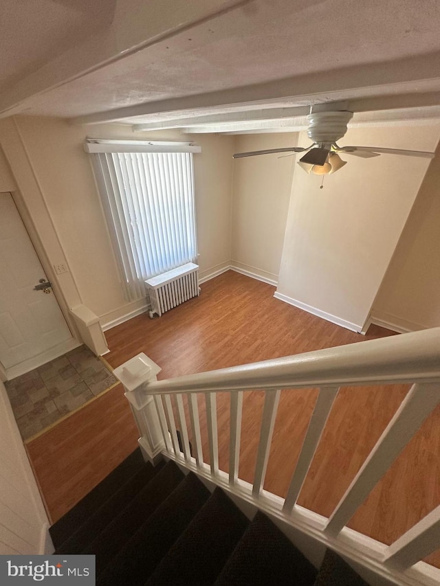 stairs featuring radiator, ceiling fan, and wood finished floors