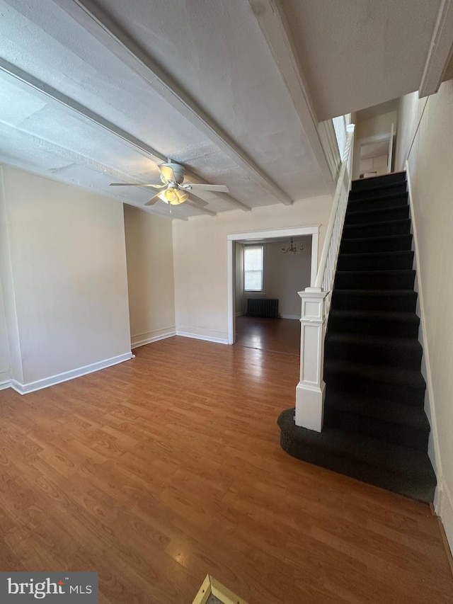 interior space with baseboards, radiator, ceiling fan, and wood finished floors