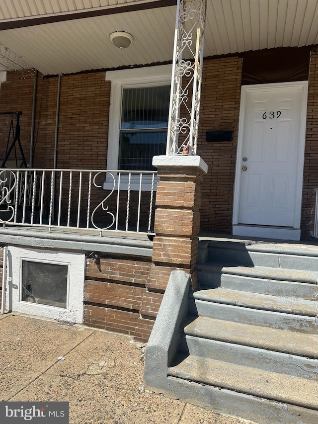 property entrance with brick siding and a porch
