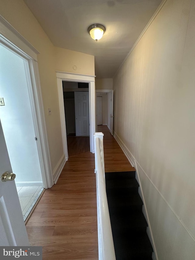 hallway featuring baseboards, stairs, and wood finished floors