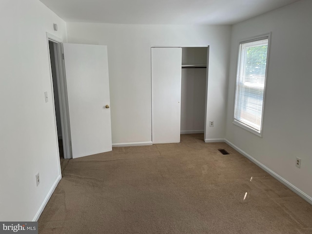 unfurnished bedroom featuring carpet floors, a closet, visible vents, and baseboards