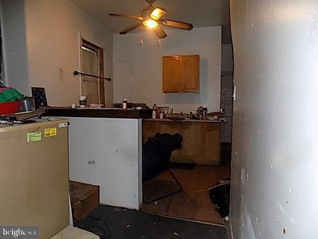 kitchen with dark tile patterned floors, stainless steel fridge, and a ceiling fan