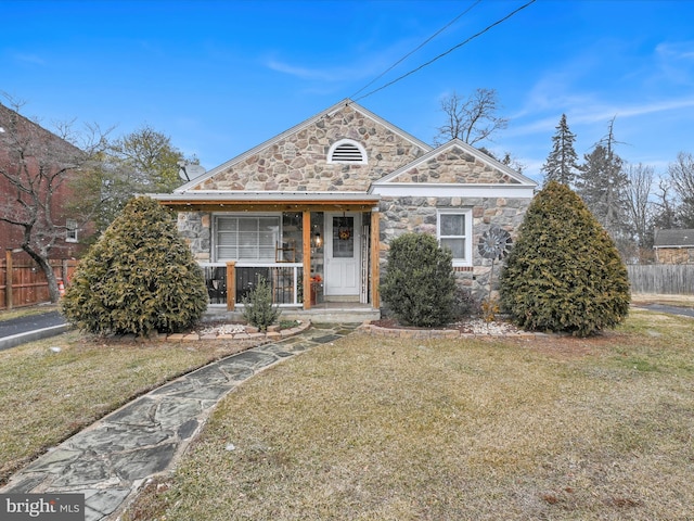 view of front of property featuring stone siding, fence, and a front lawn