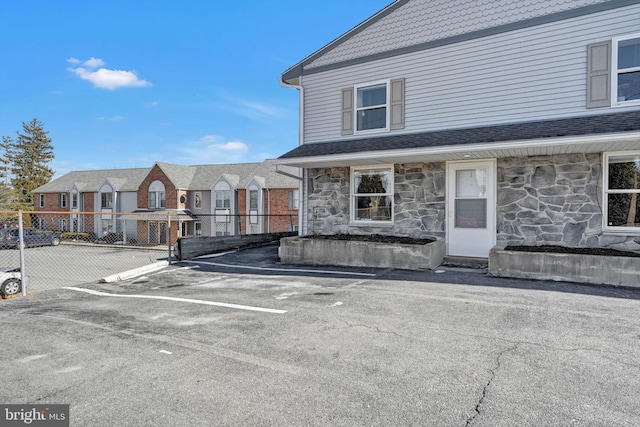 exterior space with stone siding, uncovered parking, fence, and a residential view