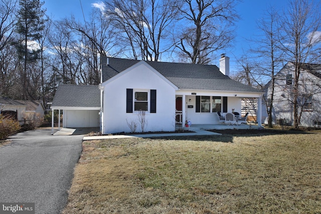 view of front of property with a chimney, a porch, a shingled roof, driveway, and a front lawn