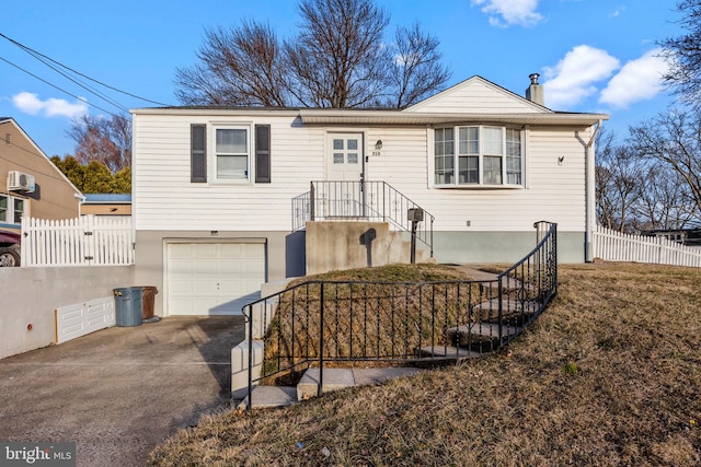 view of front of house with concrete driveway, a wall unit AC, a chimney, an attached garage, and fence