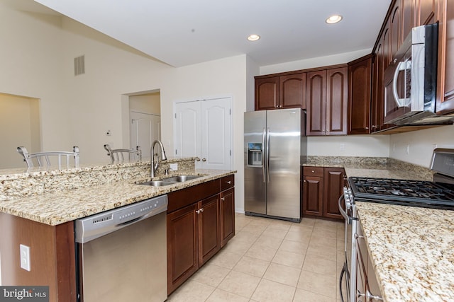 kitchen with light stone counters, a breakfast bar area, a sink, visible vents, and appliances with stainless steel finishes