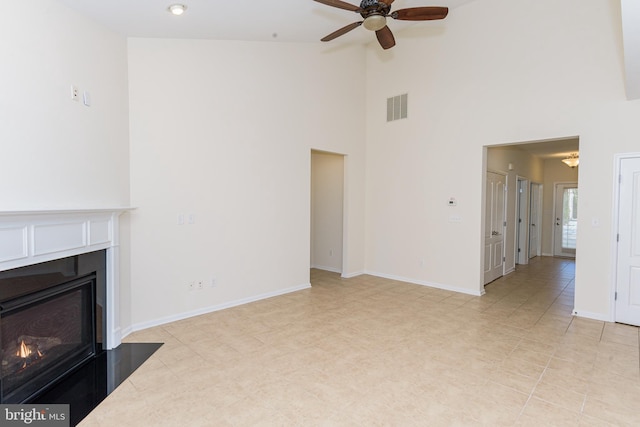 unfurnished living room featuring ceiling fan, high vaulted ceiling, a fireplace with flush hearth, visible vents, and baseboards