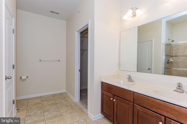 full bath with a spacious closet, visible vents, a sink, and tiled shower