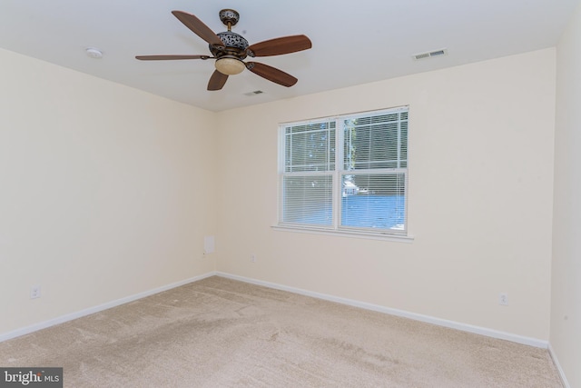 spare room with a ceiling fan, visible vents, light carpet, and baseboards