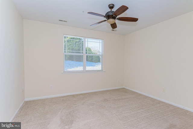 spare room with light carpet, a ceiling fan, visible vents, and baseboards