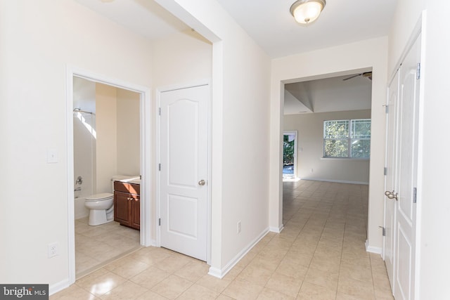 hallway featuring baseboards and light tile patterned flooring