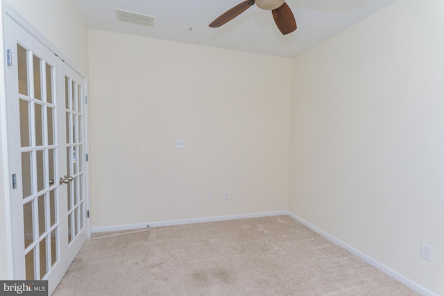 empty room featuring light carpet, baseboards, visible vents, ceiling fan, and french doors