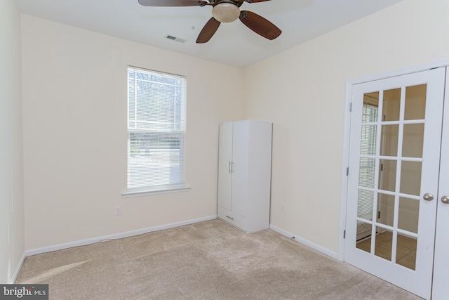 unfurnished room featuring light carpet, a ceiling fan, visible vents, baseboards, and french doors