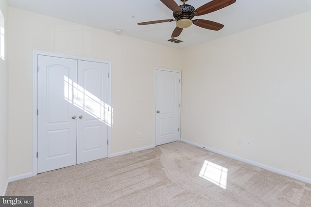 unfurnished bedroom featuring a closet, visible vents, light carpet, and baseboards