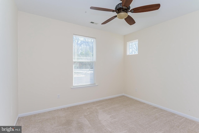 spare room with baseboards, a wealth of natural light, and light colored carpet