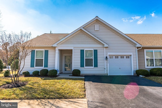 view of front facade with an attached garage, driveway, a front lawn, and a shingled roof