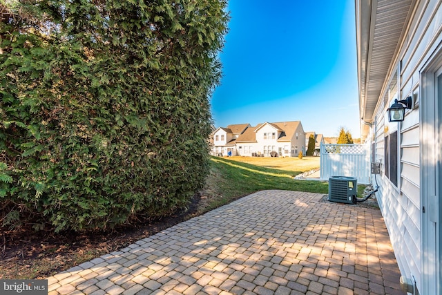 view of patio featuring a residential view, fence, and central AC unit