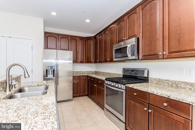 kitchen with light tile patterned floors, light stone counters, stainless steel appliances, a sink, and recessed lighting