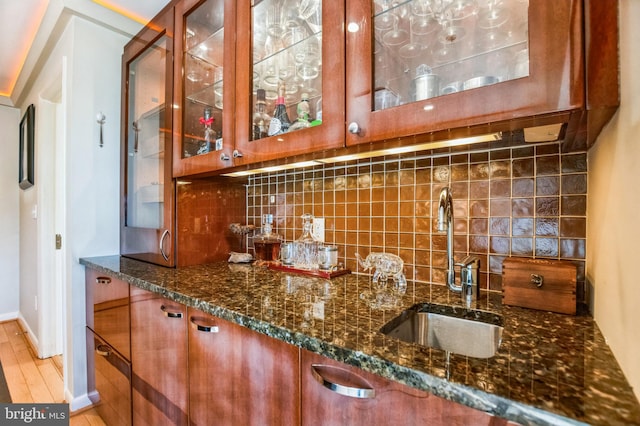 bar with tasteful backsplash, wet bar, a sink, and light wood-style flooring