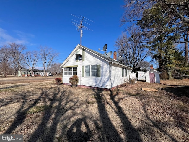 back of property with a storage shed, a chimney, and an outdoor structure