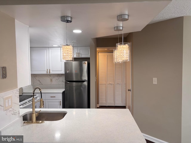 kitchen featuring freestanding refrigerator, light countertops, decorative light fixtures, and white cabinetry