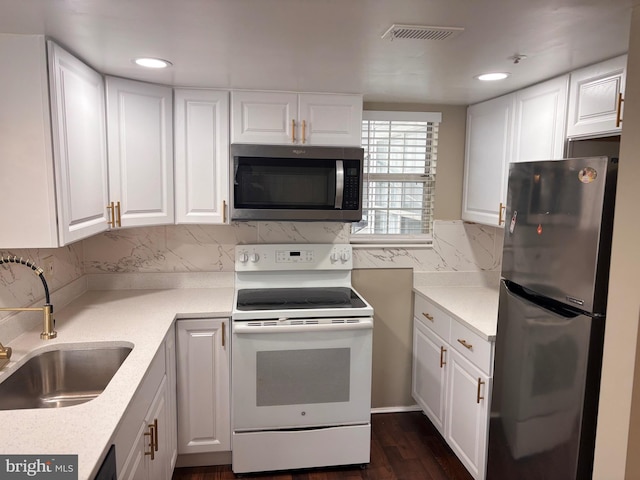 kitchen featuring stainless steel appliances, white cabinets, light countertops, and a sink