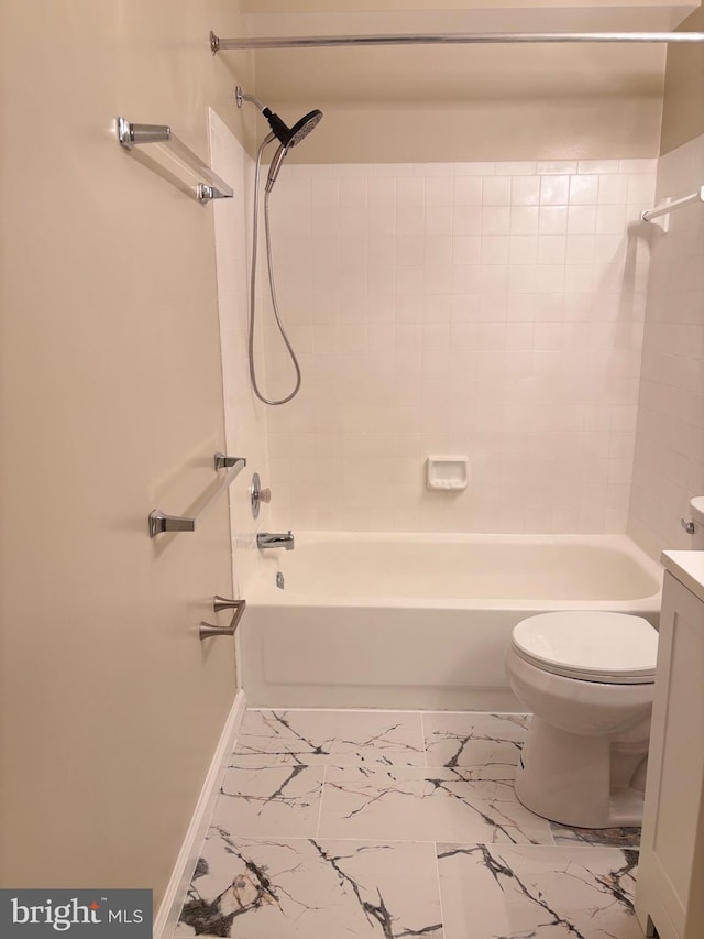 bathroom featuring marble finish floor, toilet, vanity,  shower combination, and baseboards