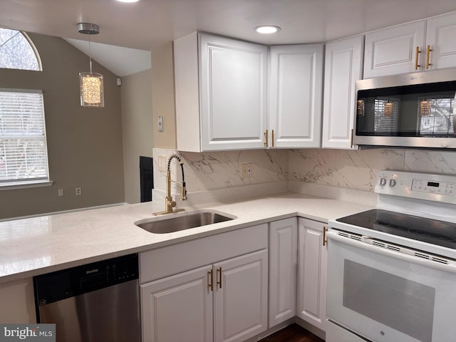 kitchen featuring appliances with stainless steel finishes, pendant lighting, white cabinets, and a sink