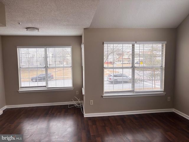 interior space featuring plenty of natural light, a textured ceiling, baseboards, and dark wood-style flooring