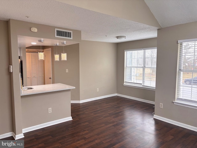 interior space with baseboards, a textured ceiling, visible vents, and dark wood-style flooring