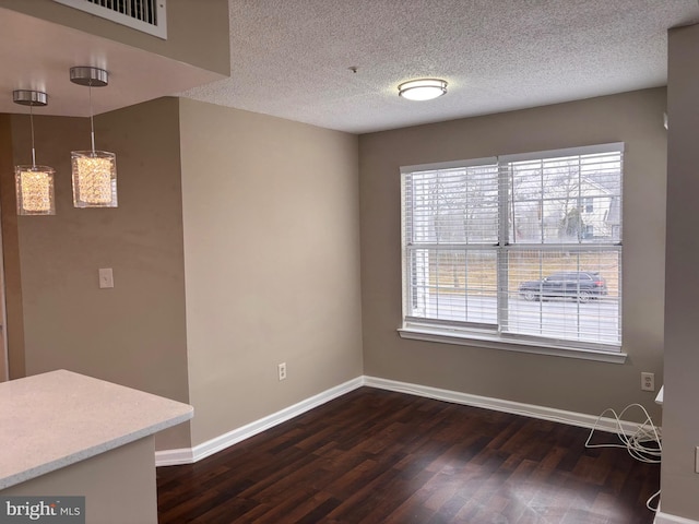 unfurnished dining area featuring a textured ceiling, dark wood-style flooring, visible vents, and baseboards