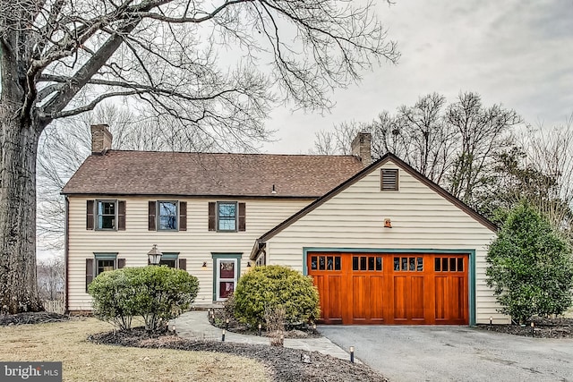 view of front of house with aphalt driveway, a chimney, and an attached garage