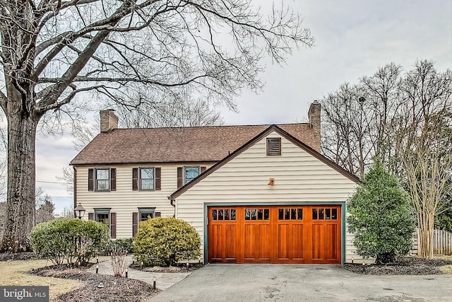 view of front of house featuring driveway, a chimney, and an attached garage