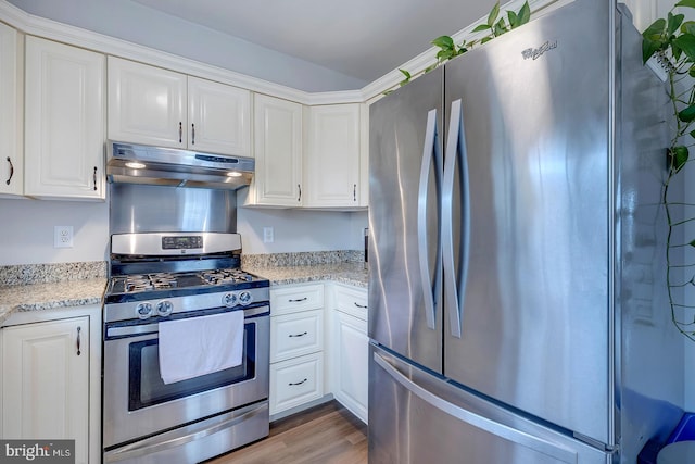 kitchen featuring appliances with stainless steel finishes, white cabinetry, light wood-style flooring, and under cabinet range hood